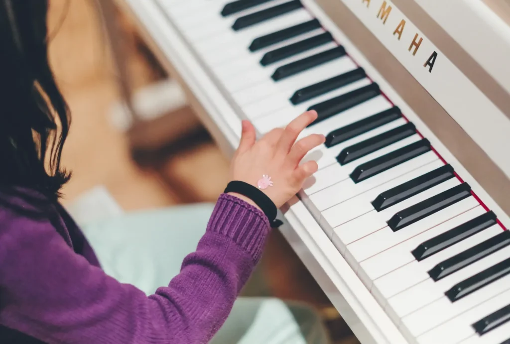 A young child practicing piano on a Yamaha keyboard, focusing on finger placement and technique.
