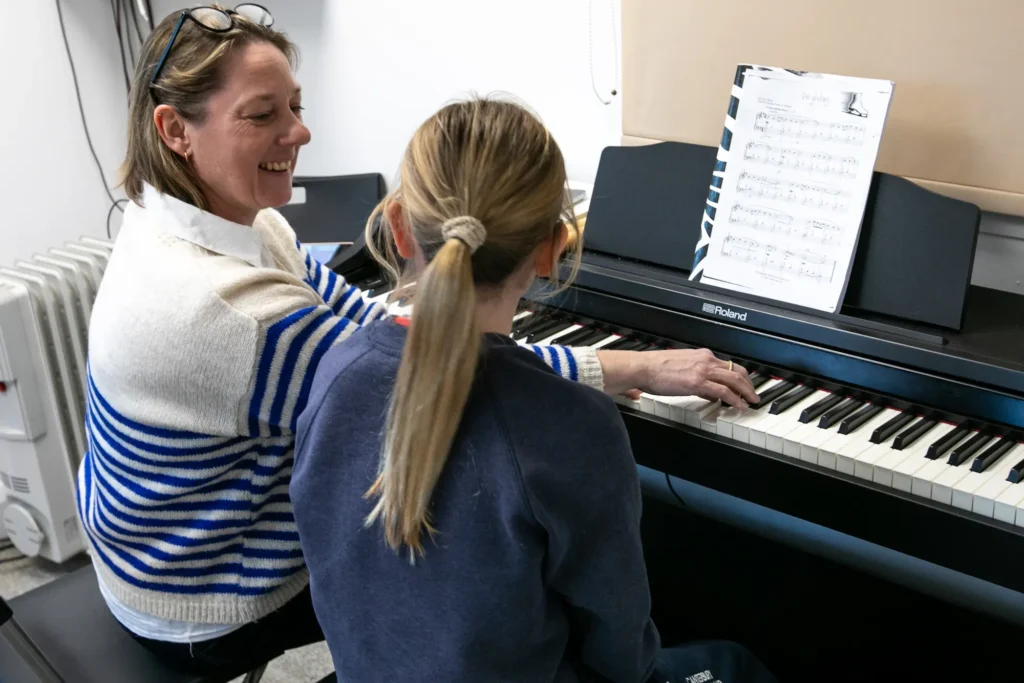 Piano teacher from The Music Works giving a private piano lesson to a school-aged child.