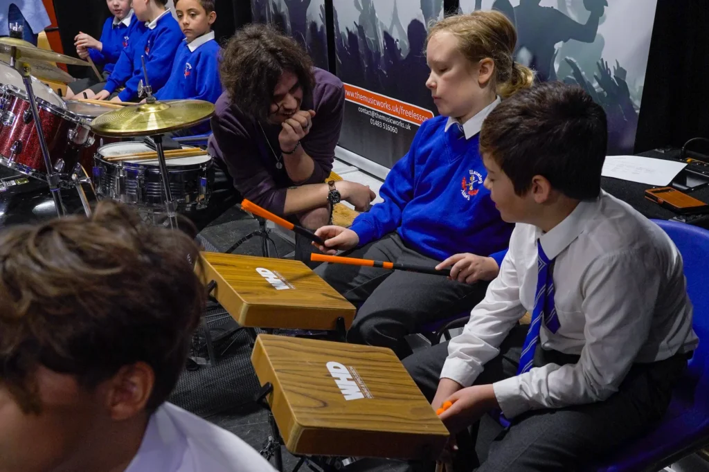 Primary school children learning percussion with a drum tutor from The Music Works