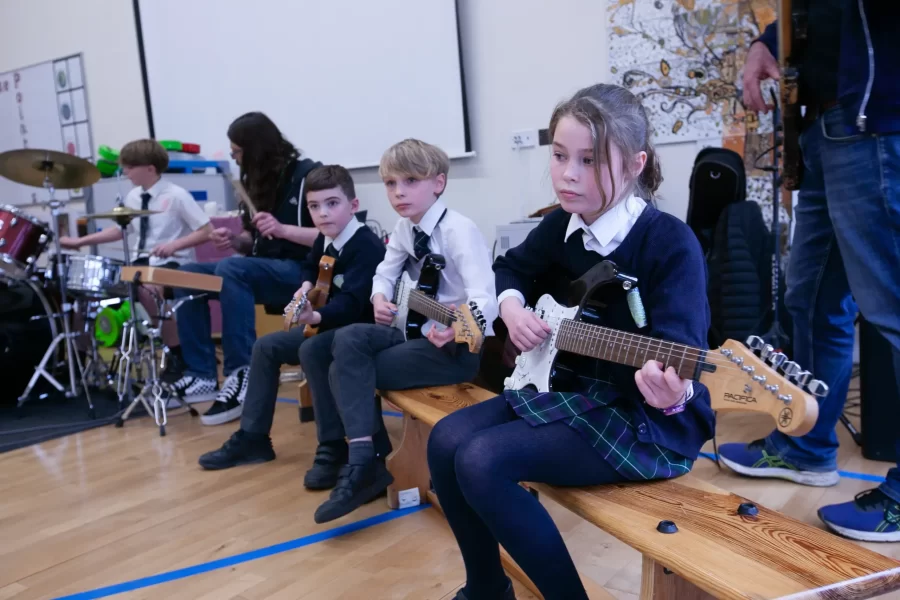 A group of students playing guitars and drums in a school band performance.