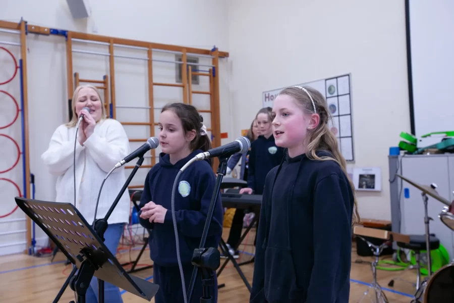 A group of students sitting on a bench, practicing electric guitar together